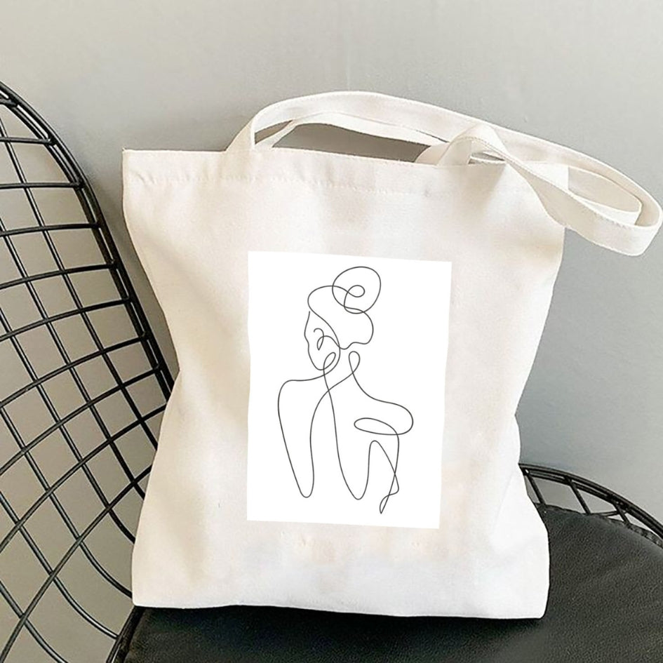 Sacoșă de pânză Kiskedves Line Art cu siluetă din spate, pe un scaun negru din sârmă.