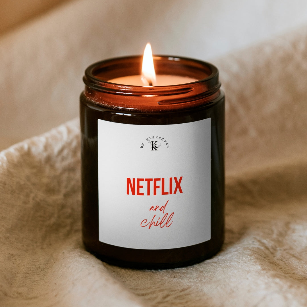 Lumânare din ceară de soia Kiskedves Netflix and chill în borcan maro, cu flacăra aprinsă, pe o pătură moale.