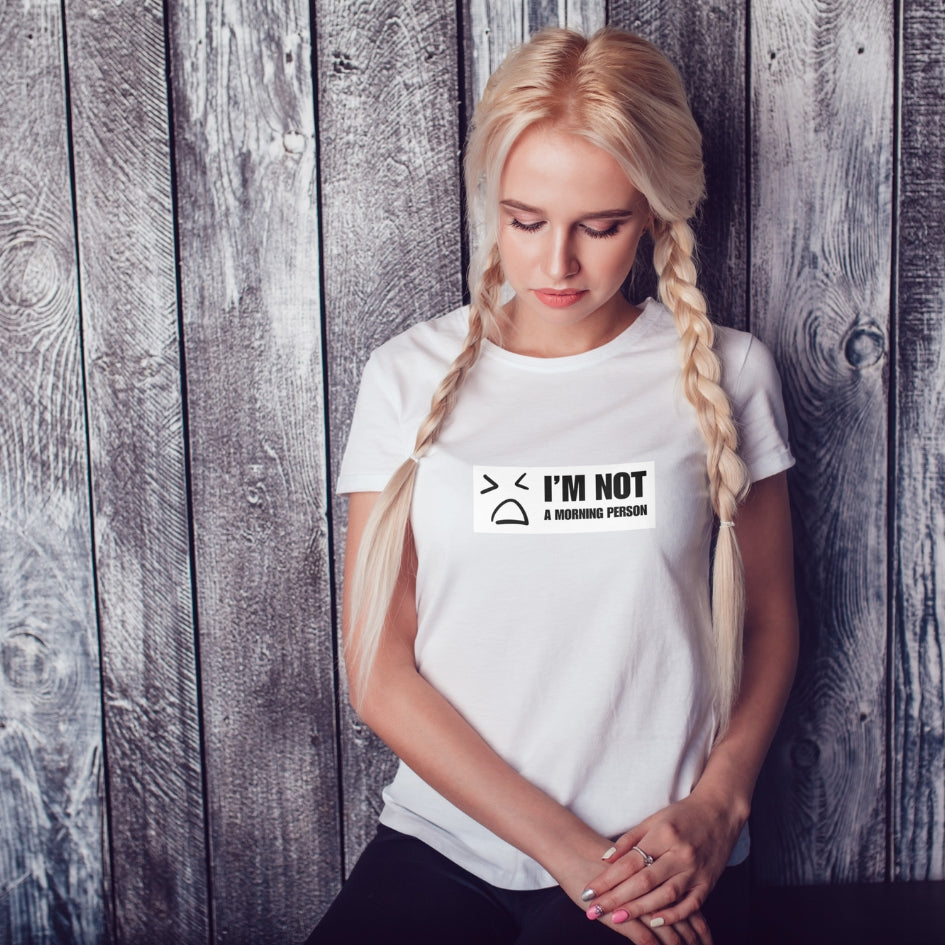 Tricou Kiskedves I'm not a morning person cu o figură desenată îmbufnată și textul I'M NOT A MORNING PERSON, pe tricou alb.