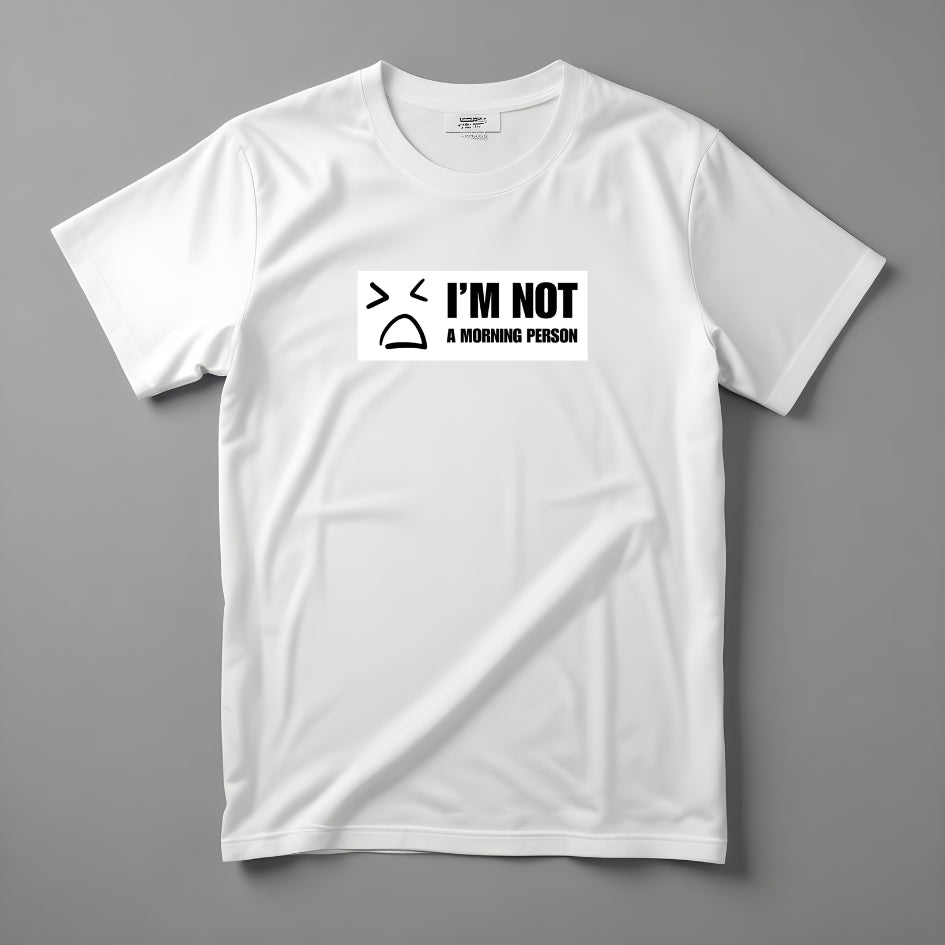 Tricou Kiskedves I'm not a morning person cu o figură desenată îmbufnată și textul I'M NOT A MORNING PERSON, fotografiat întins.