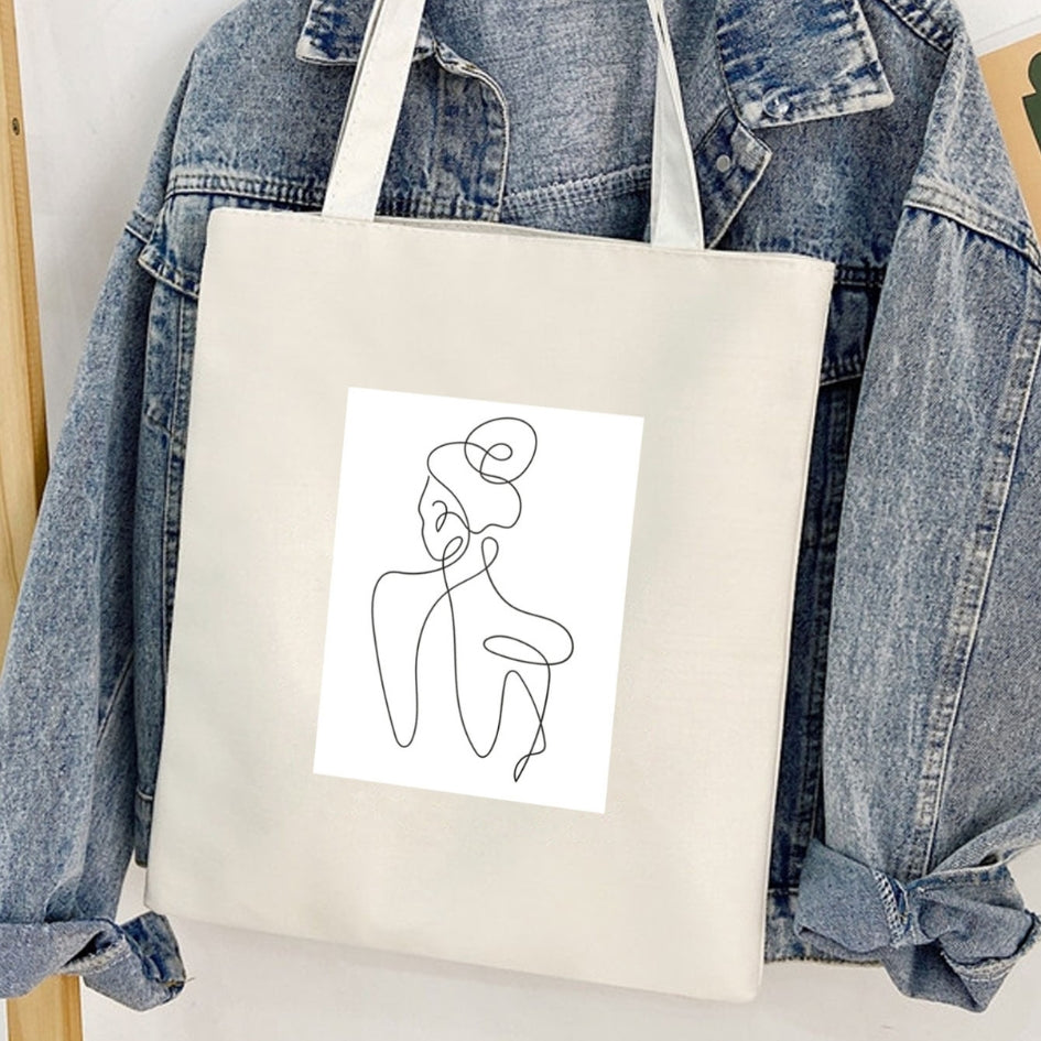 Sacoșă de pânză Kiskedves Line Art cu siluetă din spate, în fața unei geci de blugi.