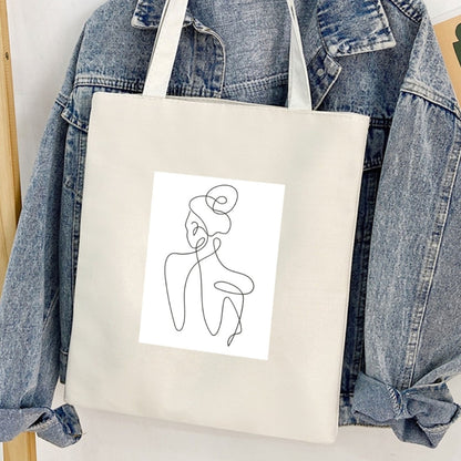 Sacoșă de pânză Kiskedves Line Art cu siluetă din spate, în fața unei geci de blugi.