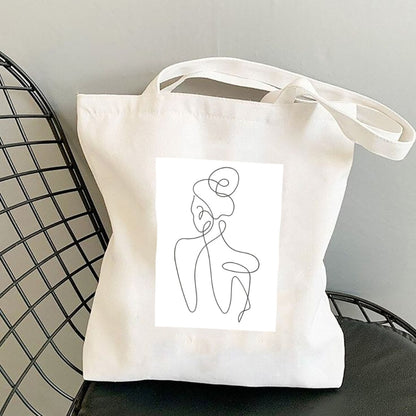 Sacoșă de pânză Kiskedves Line Art cu siluetă din spate, pe un scaun negru din sârmă.