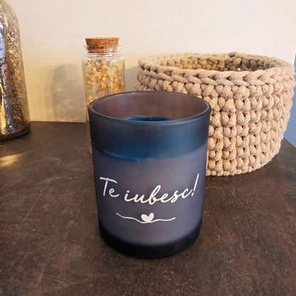 Lumânare decorativă personalizabilă Ocean fără capac, cu textul „Te iubesc”, lângă un coșuleț croșetat și o sticluță cu flori uscate