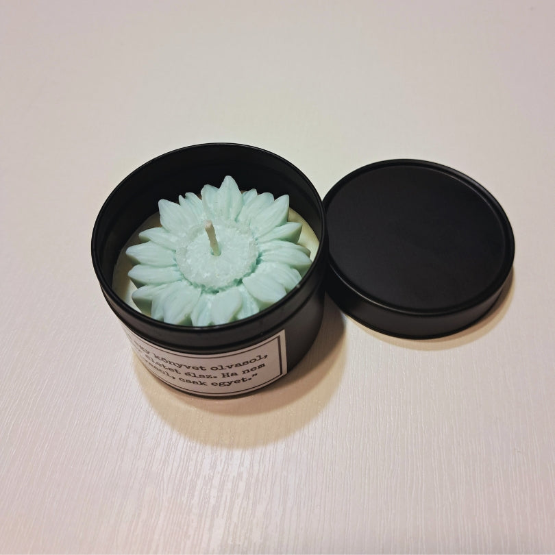 Lumânare cu flori Kiskedves în cutie metalică neagră, cu capacul alături, deasupra o floare de ceară verde pastel