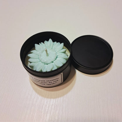 Lumânare cu flori Kiskedves în cutie metalică neagră, cu capacul alături, deasupra o floare de ceară verde pastel