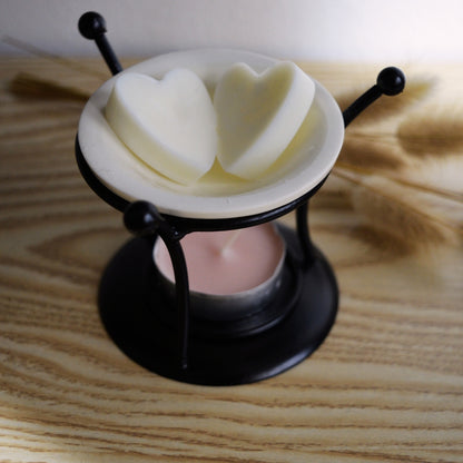Lampă aromaterapie Kiskedves cu suport metalic și bol de ceramică, în care sunt două ceruri parfumate în formă de inimă.