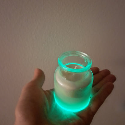 Lumânare magică Kiskedves în sticluță ținută în palmă, cu baza strălucind verde