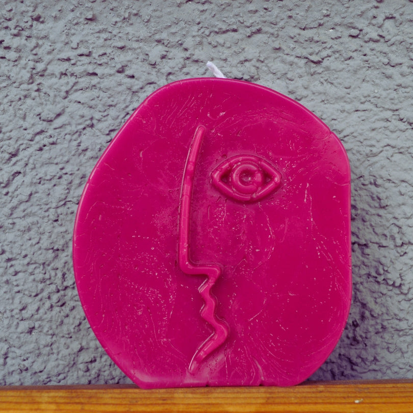 Lumânare rotundă roz Line Art cu un chip din profil trasat dintr-o singură linie și un ochi în relief, pe fundal gri