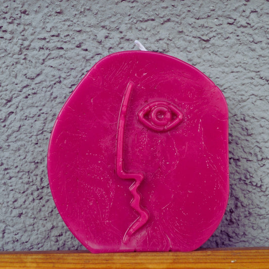 Lumânare rotundă roz Line Art cu un chip din profil trasat dintr-o singură linie și un ochi în relief, pe fundal gri