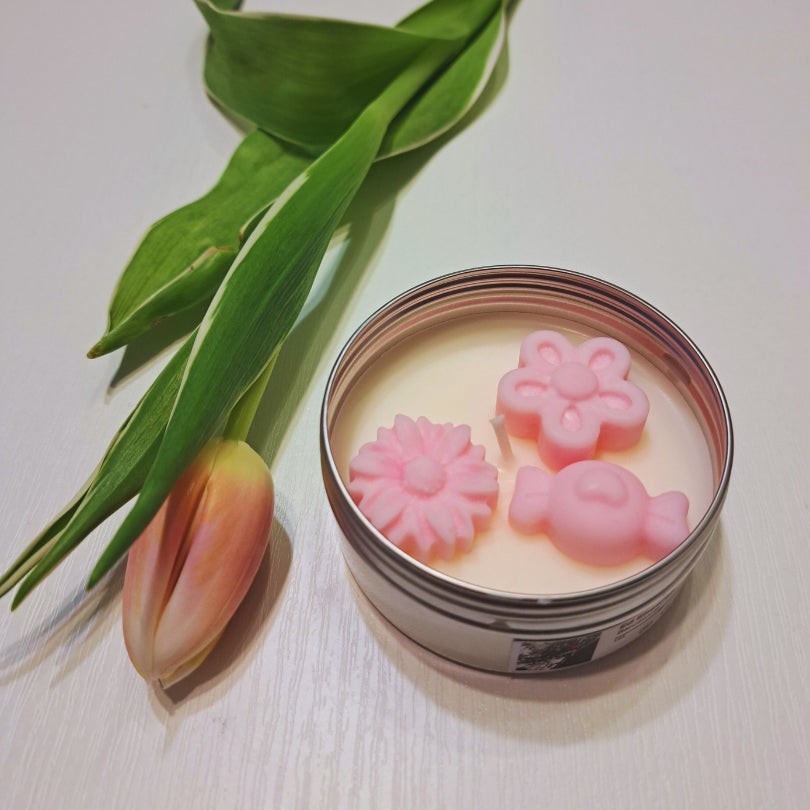 Lumânare de primăvară din ceară de soia Kiskedves în cutie metalică argintie, cu floricele și inimioare roz din ceară, alături o lalea