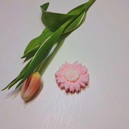 Ceară parfumată Kiskedves în formă de floare din ceară de soia, cu o lalea în fundal, pe o suprafață albă de lemn.