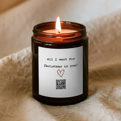 Lumânare de Crăciun „Melodică” Kiskedves aprinsă, pe etichetă inimă desenată, cod QR și mesajul All I want for Christmas is you