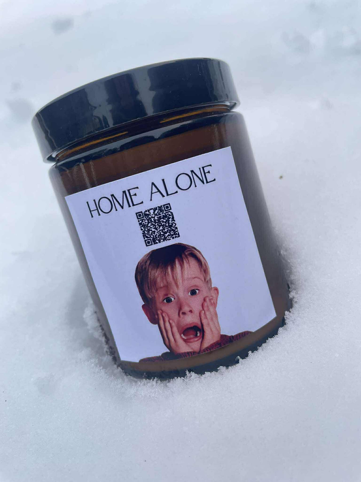 Lumânare de Crăciun „Melodică” Kiskedves în zăpadă, pe etichetă cod QR și mesajul Home Alone