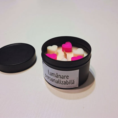Lumânare din ceară de soia cu fitil de lemn în cutie metalică neagră, cu inimioare de ceară roz și albe și eticheta „Lumânare personalizabilă”, alături capacul cutiei